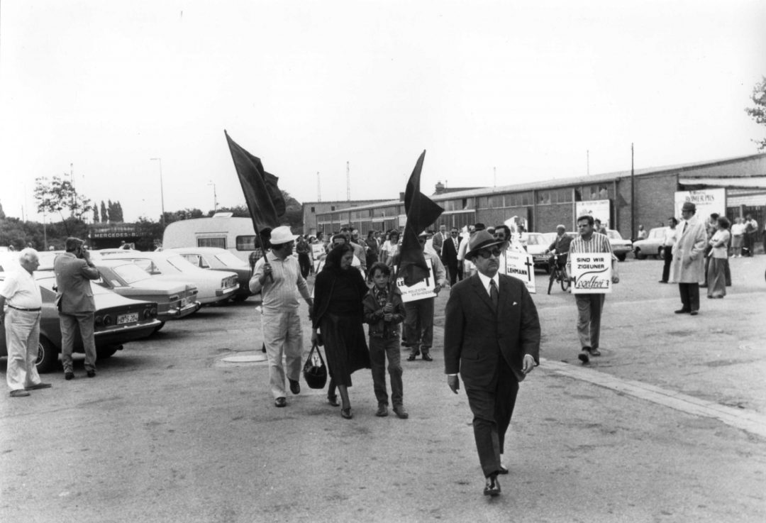 A historical black and white photo of a demonstration in Heidelberg. The occasion was the police murder of a Sinto. The civil rights activist Vinzenz Rose is walking at the beginning of the demonstration.