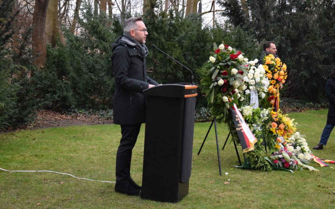 Michael Roth an einem Rednerpult während ihrer Gedenkrede am Denkmal für die ermordeten Sinti und Roma Europas in Berlin. Neben ihr stehen mehrere große, aufgeständerte Gedenkkränze.