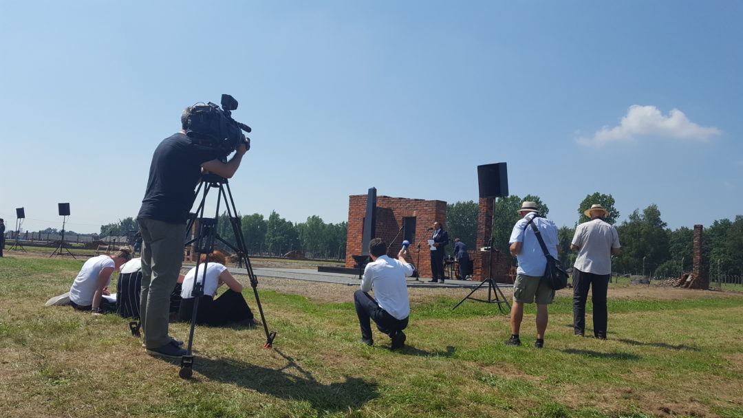 Ein Kamerateam steht vor dem Denkmal für die ermordeten Sinti und Roma in Auschwitz-Birkenau.