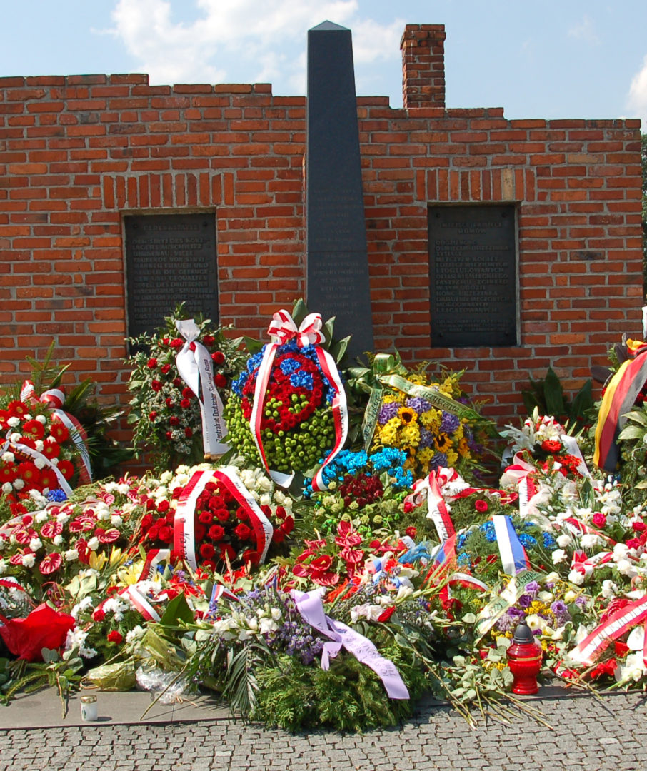 Das Denkmal in Auschwitz-Birkenau. Davor liegen dutzende von Trauerkränzen.