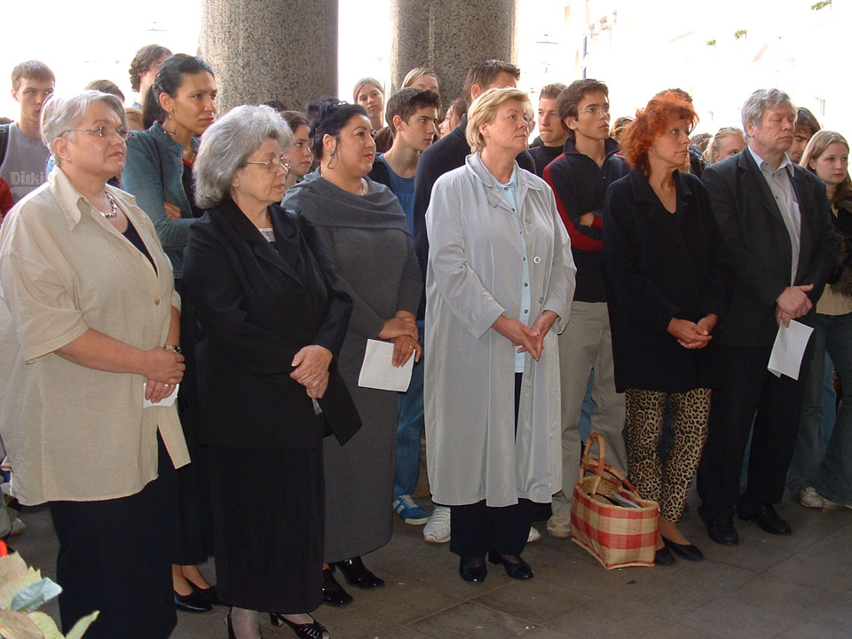 Teilnehmerinnen und Teilnehmer stehen im Halbkreis während der Gedenkveranstaltung.