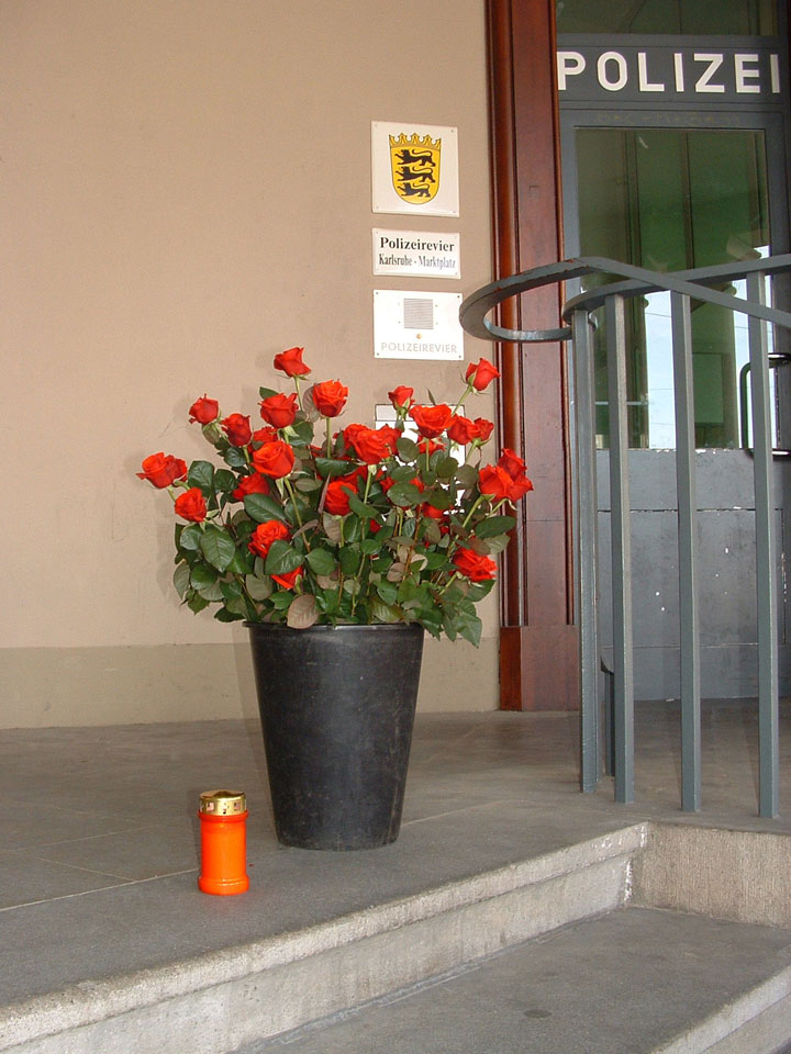 Blumen und eine Grabkerze zum Gedenken vor dem Polizeirevier