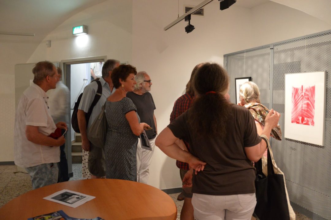 Ausstellungseröffnung von Alfred Ullrich. Besucherinnen und Besucher betrachten die Bilder des Künstlers.