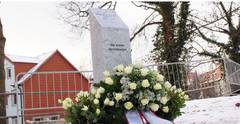 Bild der Gedenkstele in Merseburg. Davor ein Blumenkranz zum Gedenken.