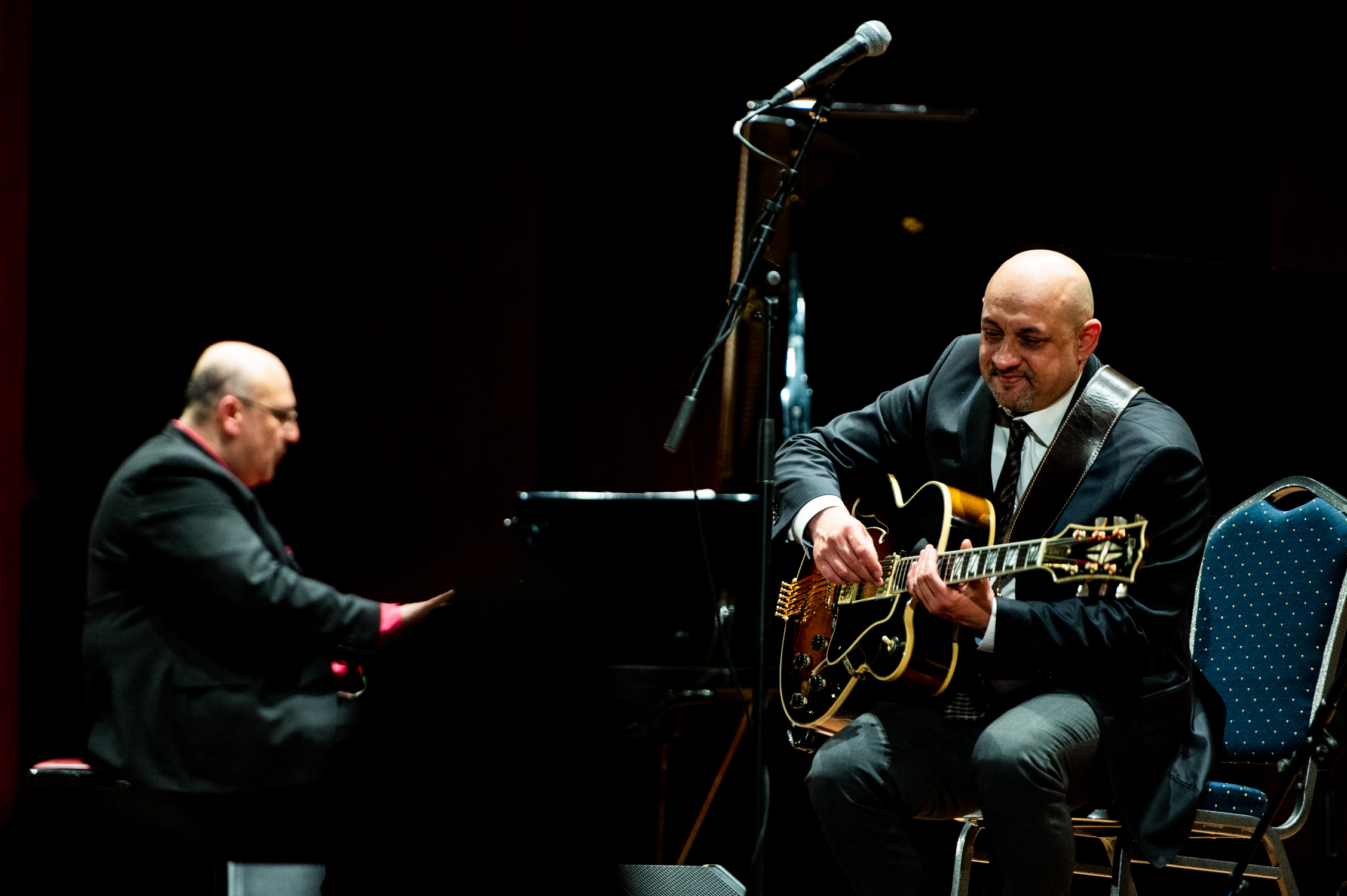 Auf einer Bühne: Links sitzt ein Mann an einem Flügel, rechts ein Mann mit Gitarre.