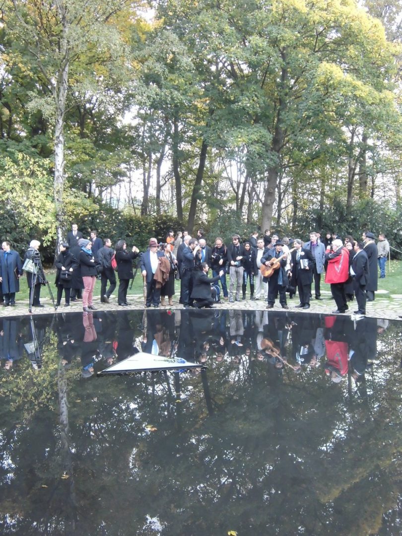 Teilnehmerinnen und Teilnehmer am Wasserbecken des Denkmals für die ermordeten Sinti und Roma in Berlin