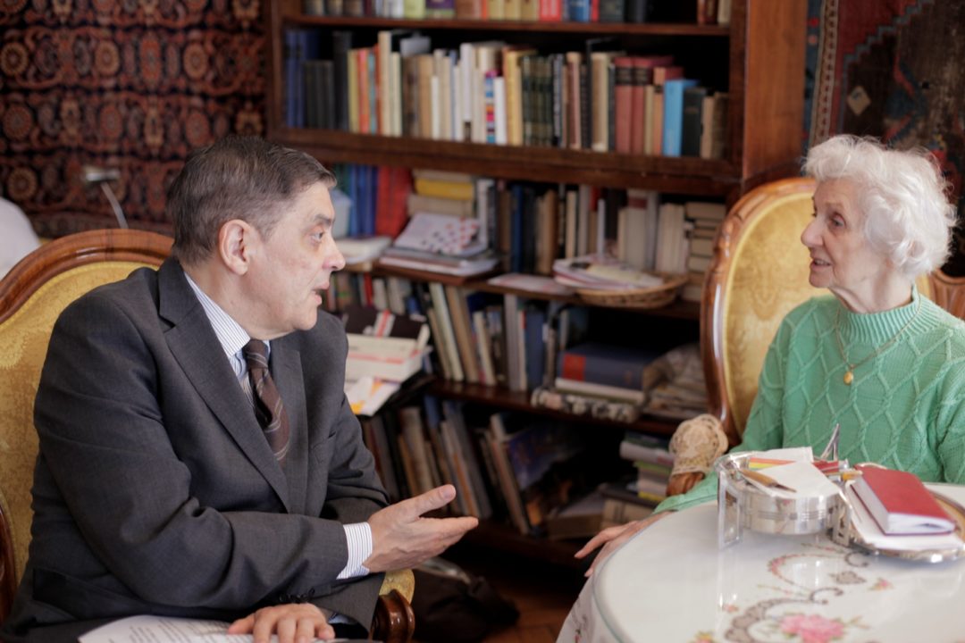 Romani Rose führt am 1. März 2014 in Budapest ein Interview mit der Holocaust-Überlebenden Éva Fahidi-Pusztai. Beide sitzen zusammen in Sesseln an einem Kaffeetisch.