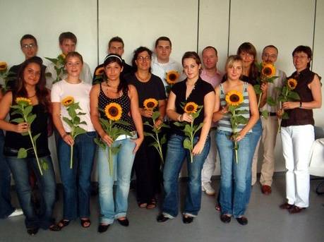 Gruppenbild beim Abschluss. In der ersten Reihe halten die Teilnehmerinnen und Teilnehmer Sonnenblumen in den Händen.