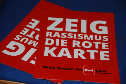 Zwei Flyer der Aktion "Zeig Rassismus die rote Karte". Der Name der Aktion ist in großen Buchstaben auf rotem Grund gedruckt.
