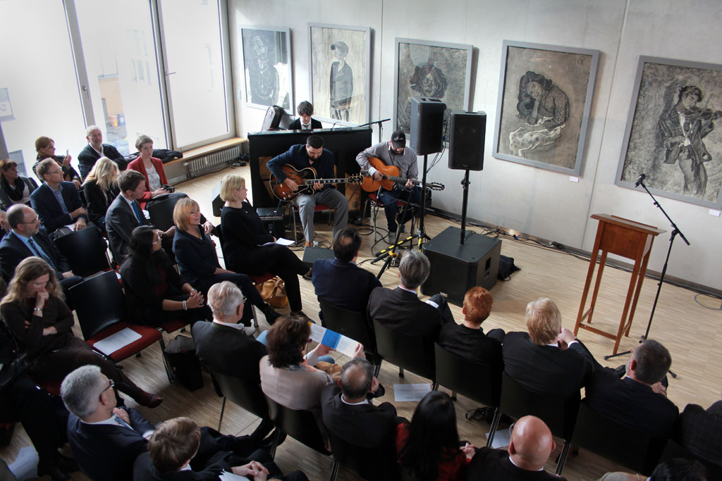 Musikbeitrag während der Eröffnung. Blick von der Galerie auf Musiker und Publikum unten.