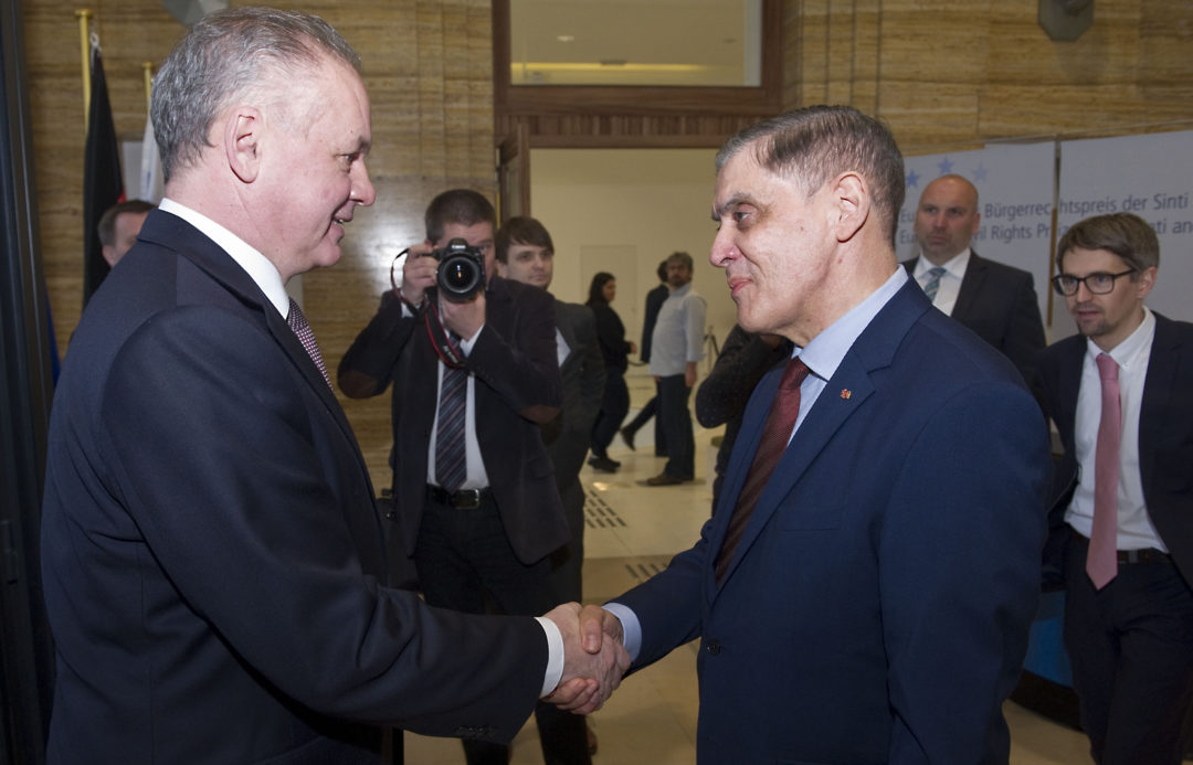 Romani Rose and Andrej Kiska shake hands as they greet each other.