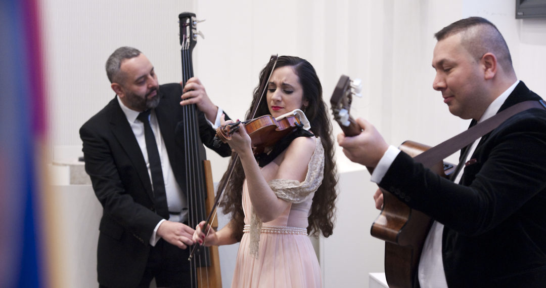 Drei Musiker während ihres Auftritts. Ein Mann spielt den Kontrabass, eine Frau an der Violine und ein Gitarrist.