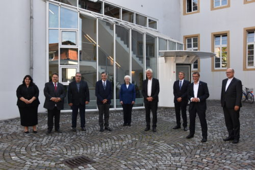 Vorstandsmitglieder des Zentralrats Deutscher Sinti und Roma und Vertreter*innen der EKD auf einem Gruppenbild im Innenhof des Dokumentations- und Kulturzentrums.