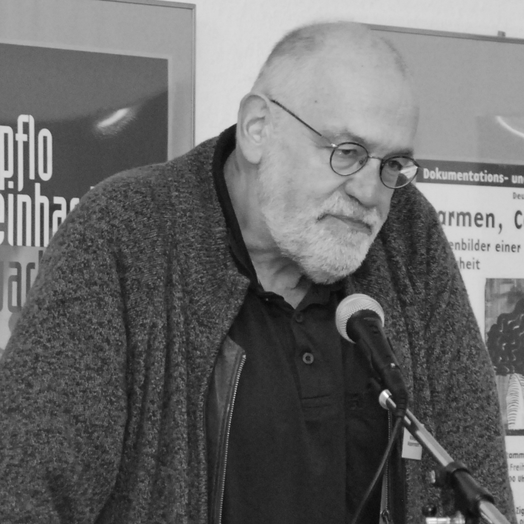 Schwarz-weiß-Foto von Wolgang Wippermann, der sich während eines Vortrags auf ein Rednerpult stützt.