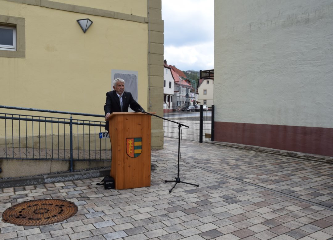 Manfred Lautenschläger steht an einem Rednerpult vor der Gedenktafel in Hoffenheim.