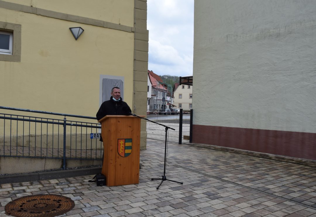 Oberbürgermeister Jörg Albrecht steht an einem Rednerpult vor der Gedenktafel.