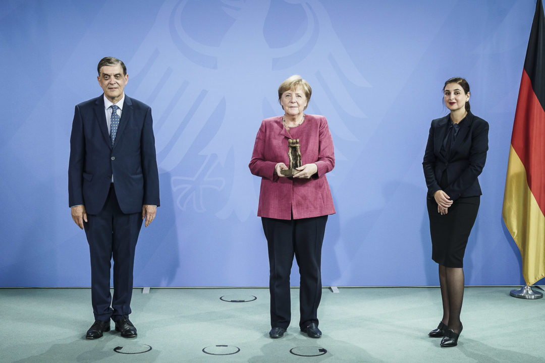 Romani Rose, Angela Merkel und Dotschy Reinhardt bei der Übergabe des Preises im Bundeskanzleramt einige Monate nach der Verleihung. Angela Merkel hält die Statue des Bürgerrechtspreises in ihren Händen.