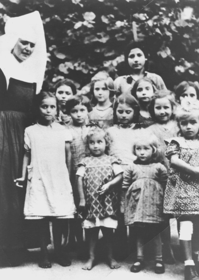 Gruppenbild von Sinti-Kindern im Kinderheim der St. Josefspflege in Mulfingen in den 1930er oder 1940er Jahren. Am linken Bildrand ist eine Nonne im Habit zu sehen.