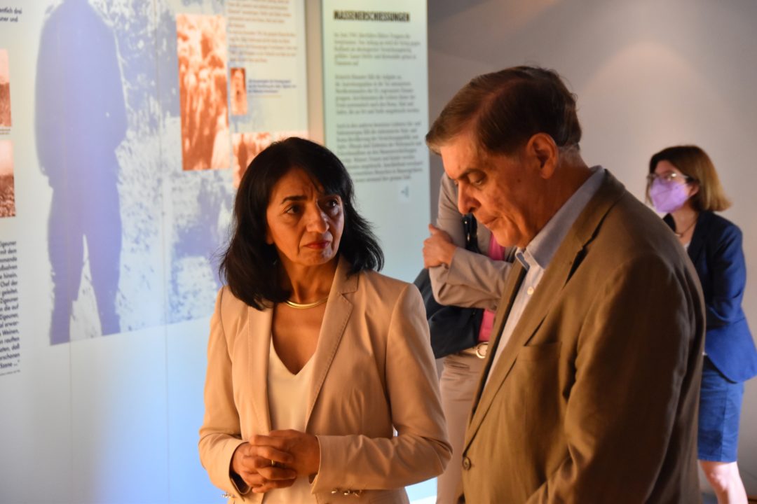 Landtagspräsidentin Muhterem Aras ist in ein Gespräch mit Romani Rose vertieft. Im Hintergrund ist ein Teil der Ausstellung des Dokumentations- und Kulturzentrums zu sehen.