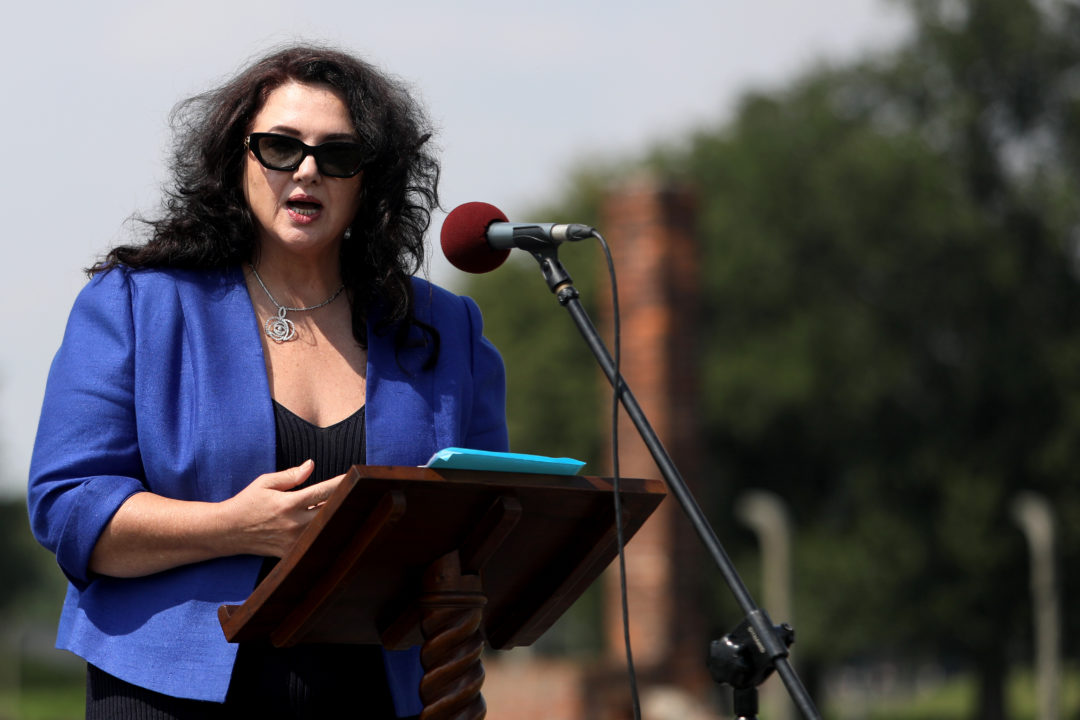 Helena Dalli stands at a wooden lectern and speaks into a microphone.