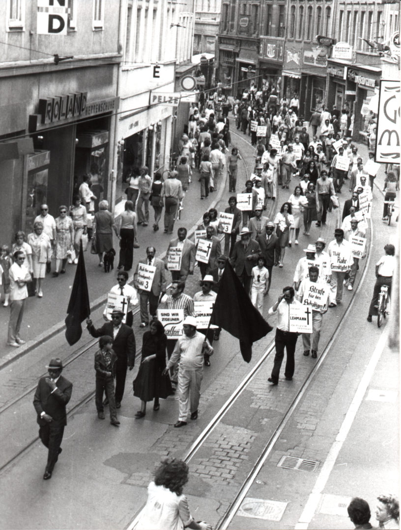 Das Foto zeigt den Schweigemarsch der Demonstranten durch die Heidelberger Innenstadt. Am Beginn des Protestzug läuft Vinzenz Rose, ihm folgen zahlreiche Demonstrierende mit Plakaten, Bannern und schwarzen Trauerfahnen.