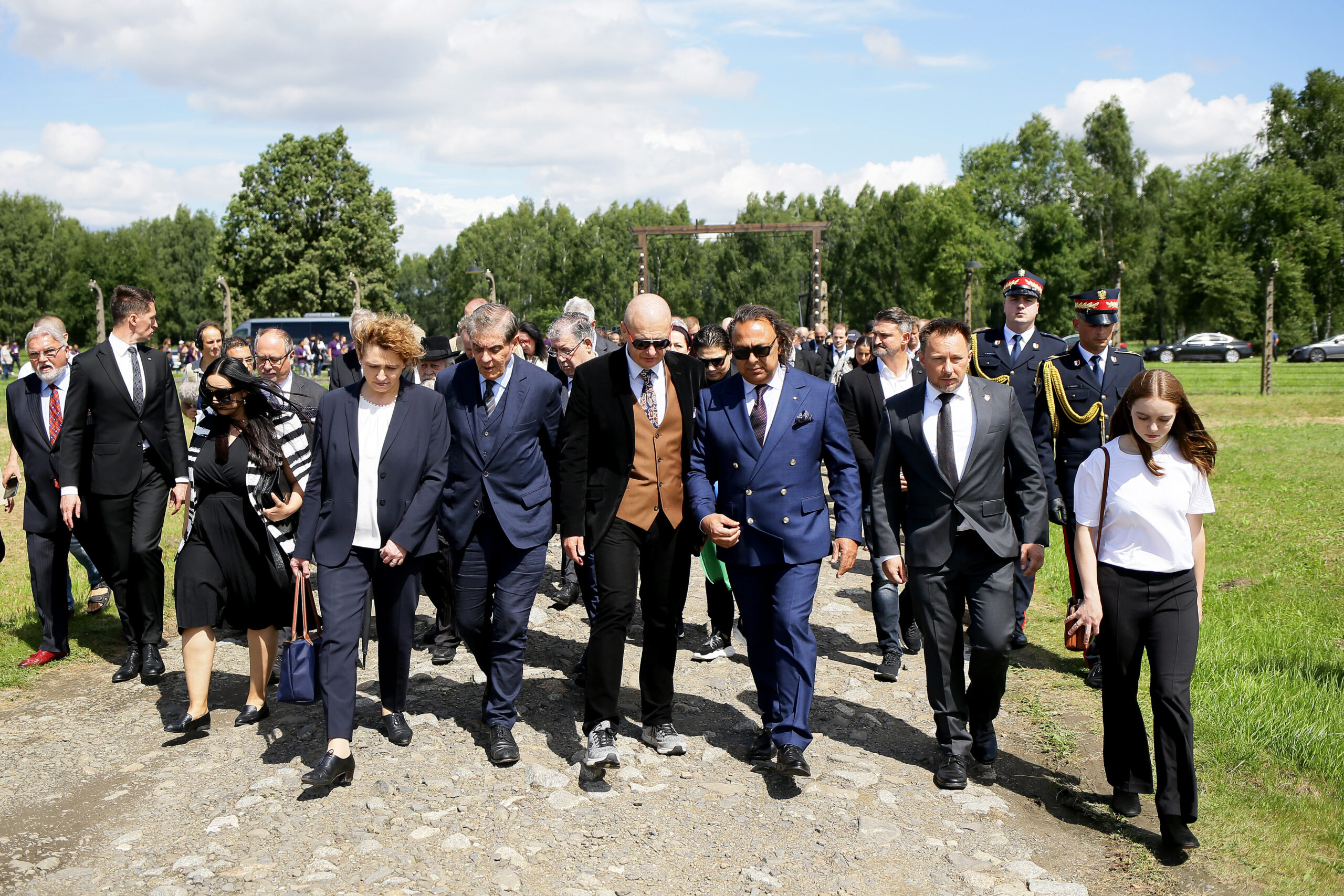 Teilnehmer*innen des Europäischen Holocaust-Gedenktag für Sinti und Roma am 2. August 2023 laufen auf einem steinigen Weg zum Denkmal in Auschwitz-Birkenau.